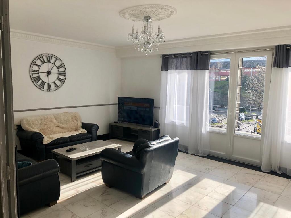 a living room with couches and a tv and a clock at Grand appartement de standing "Rêve du Soir" de 170 m2 350 m de la gare in Lourdes