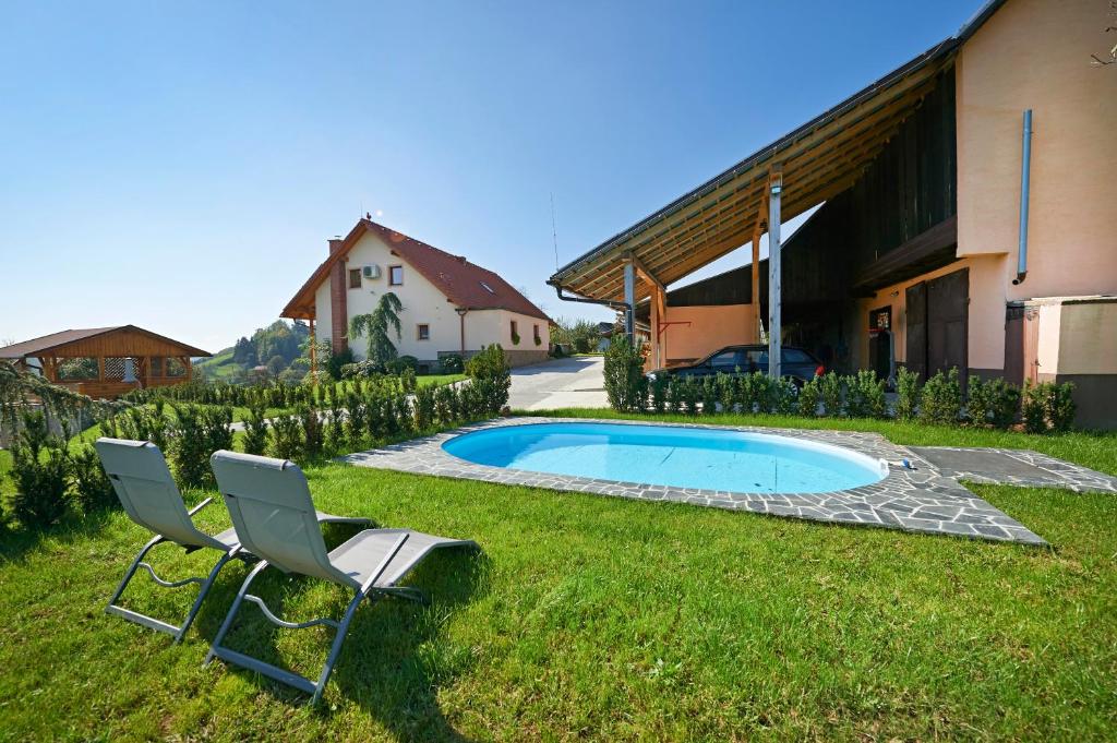 een tuin met 2 stoelen en een zwembad bij Farmhouse Lipoglav in Loče pri Poljčanah