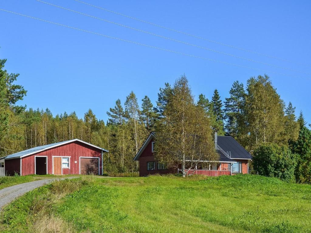 a red barn on a grassy hill next to a road at Holiday Home Oriaho by Interhome in Iisalmi