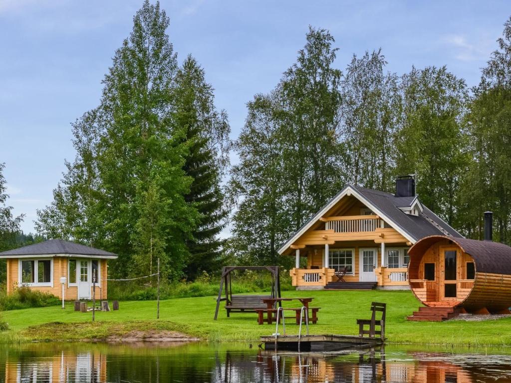 Holiday Home Kissaniemi by Interhome في إيسلمي: كابينة خشبية مع ملعب بجوار البحيرة