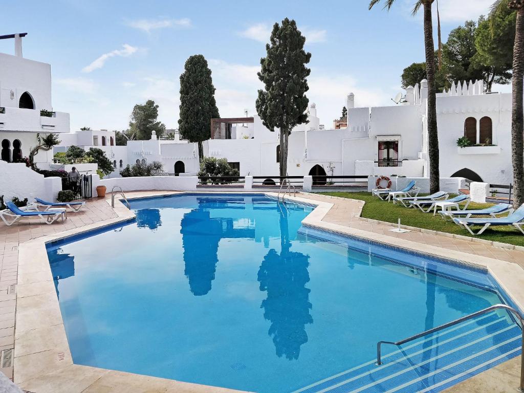una piscina con agua azul frente a una casa blanca en Apartment Pueblo Arabesque, en Marbella