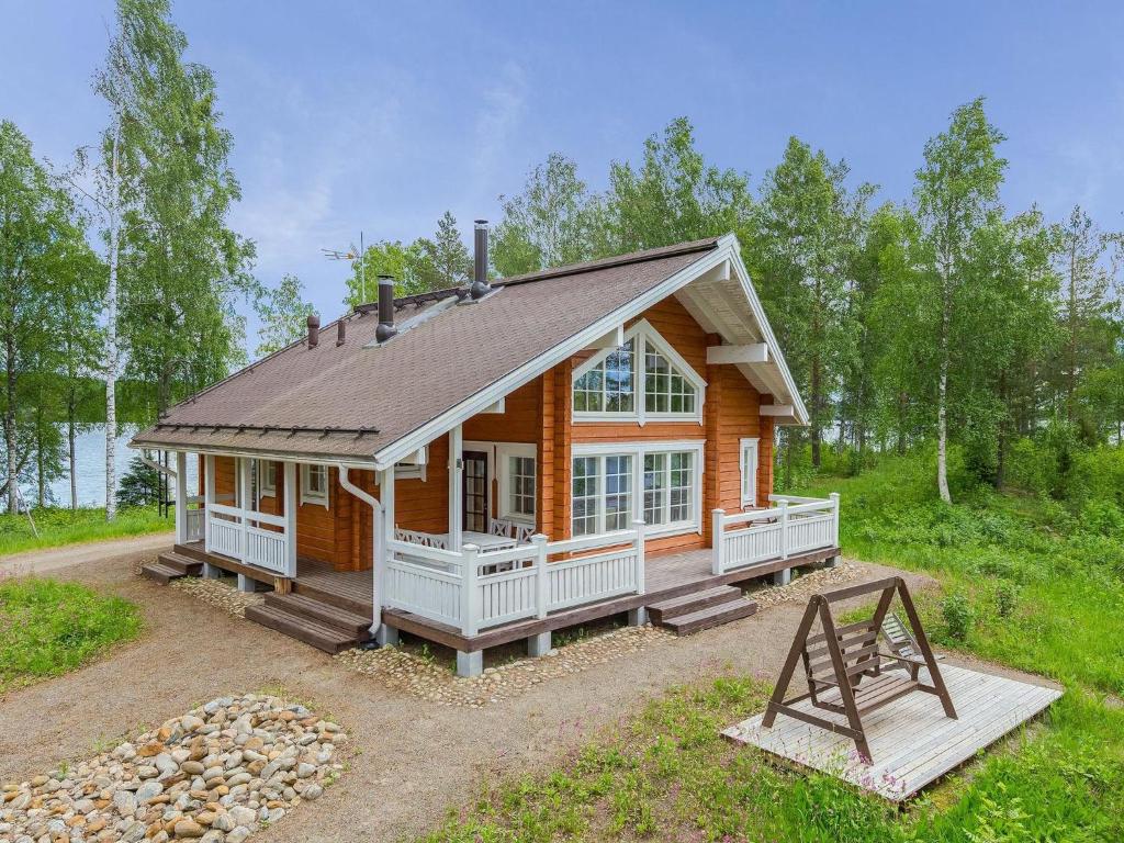 een blokhut met een gambrel dak en een veranda bij Holiday Home Paavolanniemi by Interhome in Kotalahti