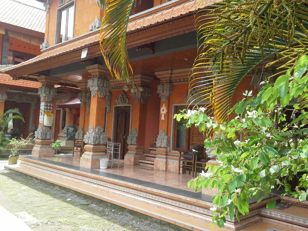 um edifício com um alpendre com cadeiras e plantas em Pica Sedana Homestay em Ubud