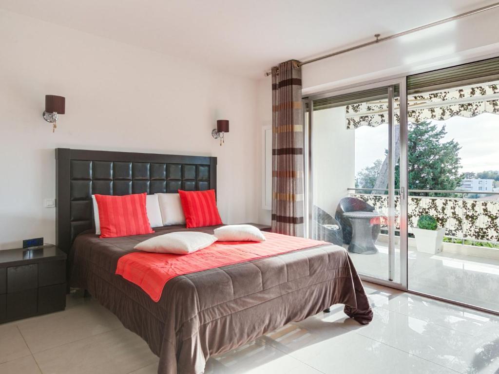 a bedroom with a large bed with red pillows at Apartment Les Pins D&#39;Alep by Interhome in Le Cannet