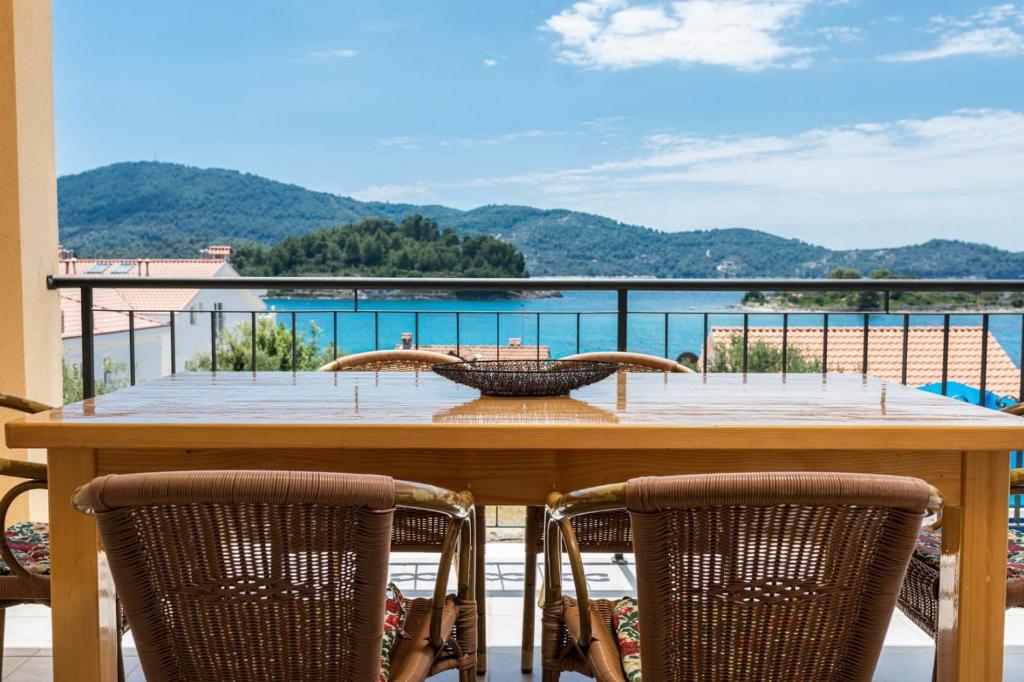 a table on a balcony with a view of the water at Apartments Fran in Vela Luka