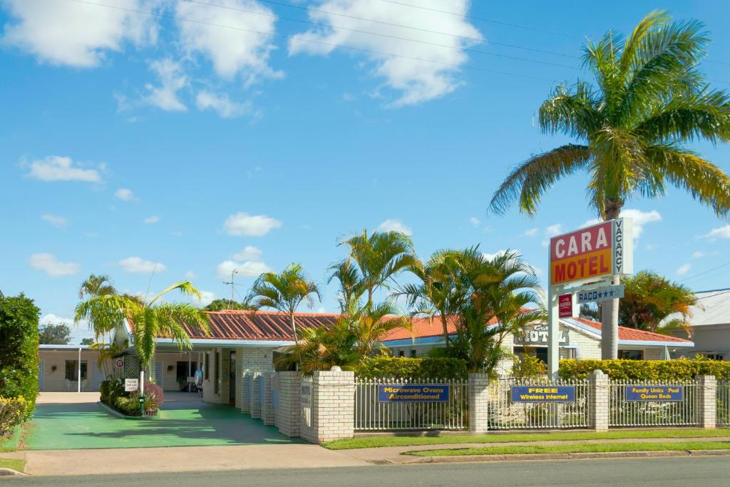 a carnegie motel with a sign and palm trees at Cara Motel in Maryborough