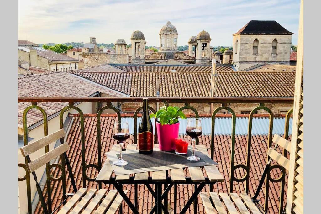 ニームにあるSur les toits de Nîmesのバルコニーにテーブルとワイン2杯