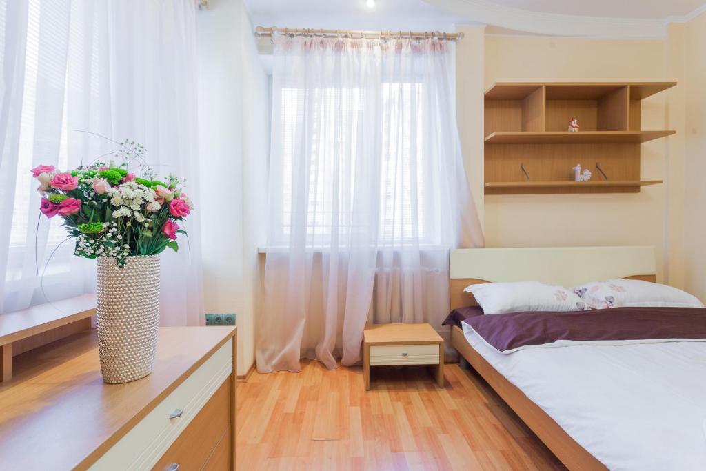 a bedroom with a bed and a vase with flowers at Апартаменты возле МВЦ in Kyiv