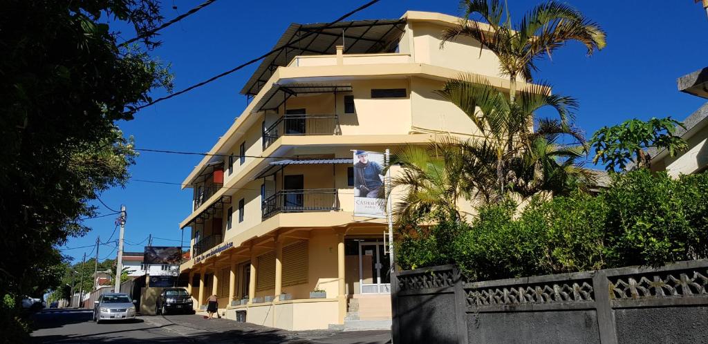 a tall yellow building with a palm tree in front of it at Bobato building in Curepipe