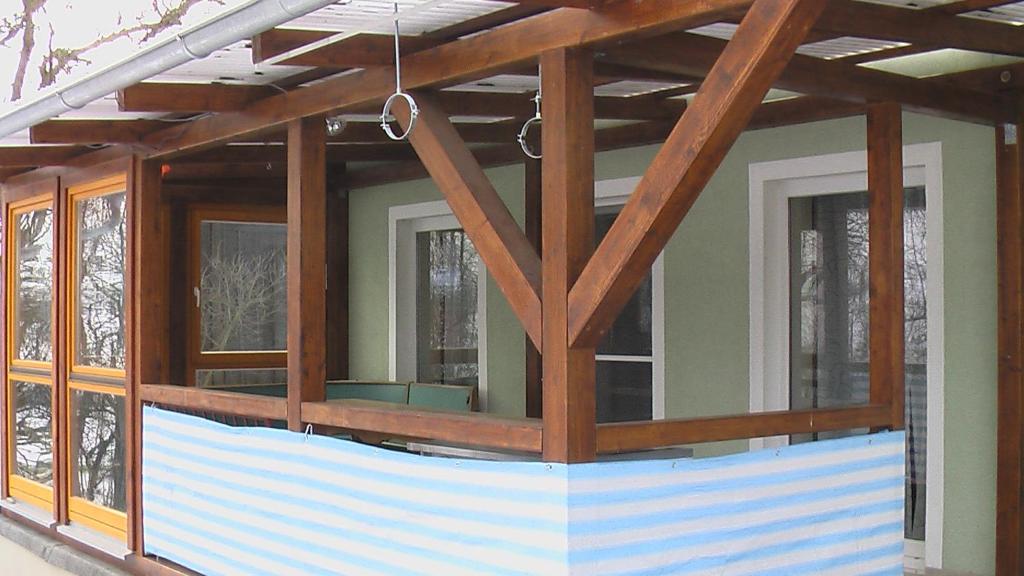 a screened in porch on a house with windows at FeWo am Schlossberg in Neusitz