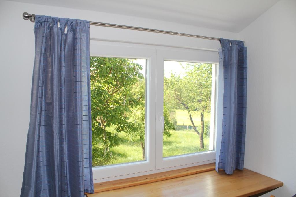una ventana con cortinas azules en una habitación en FeWo am Schlossberg, en Neusitz