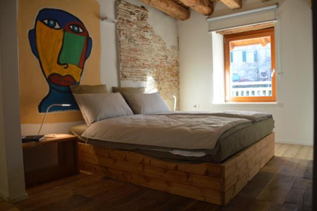 a bedroom with a bed with a painting on the wall at Le Stanze di Klaus in Rovereto
