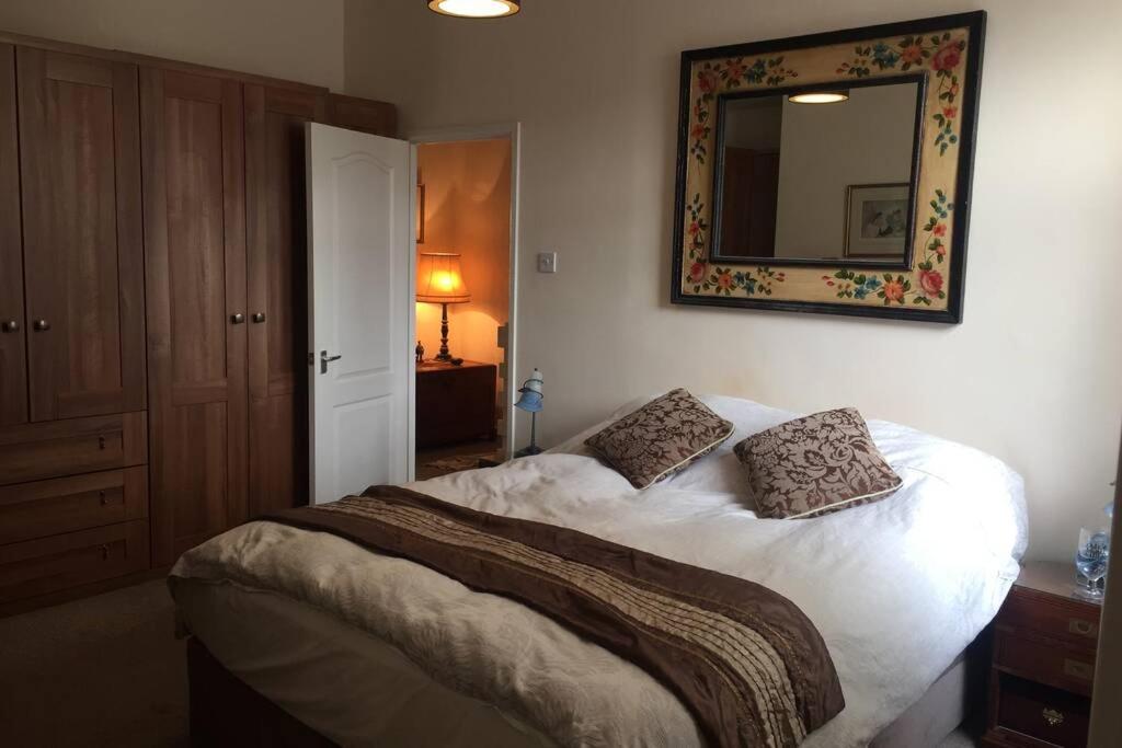 1 dormitorio con 1 cama con espejo en la pared en Foreman's Cottage, en Seaton Delaval