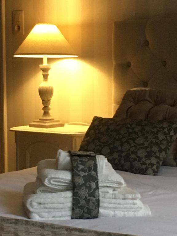 a pile of towels on a bed next to a lamp at La MeusÂme in Dinant