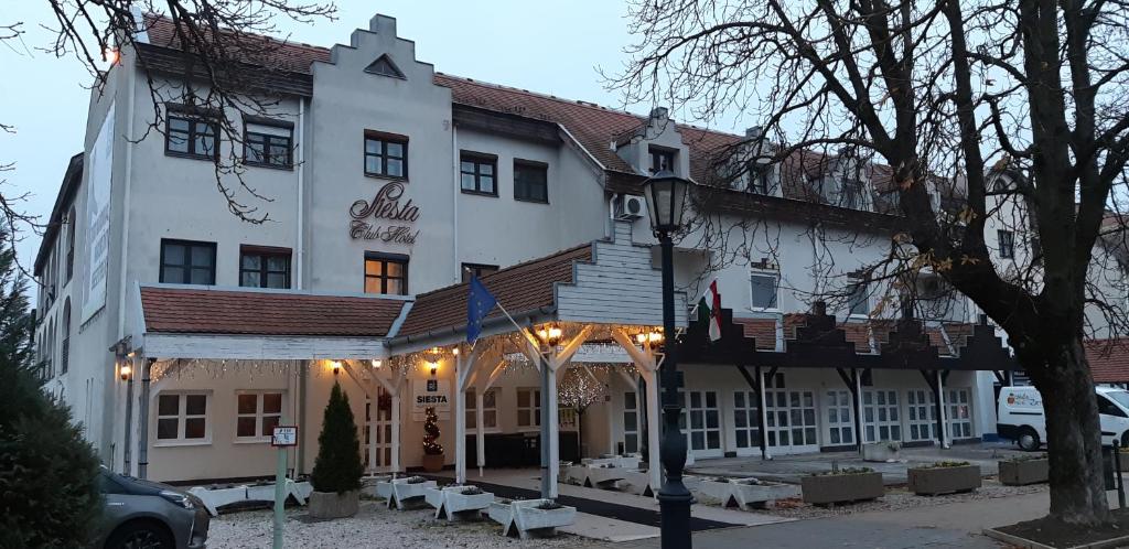 Un grand bâtiment blanc avec des lumières sur lui dans l'établissement Siesta Club Hotel, à Harkány