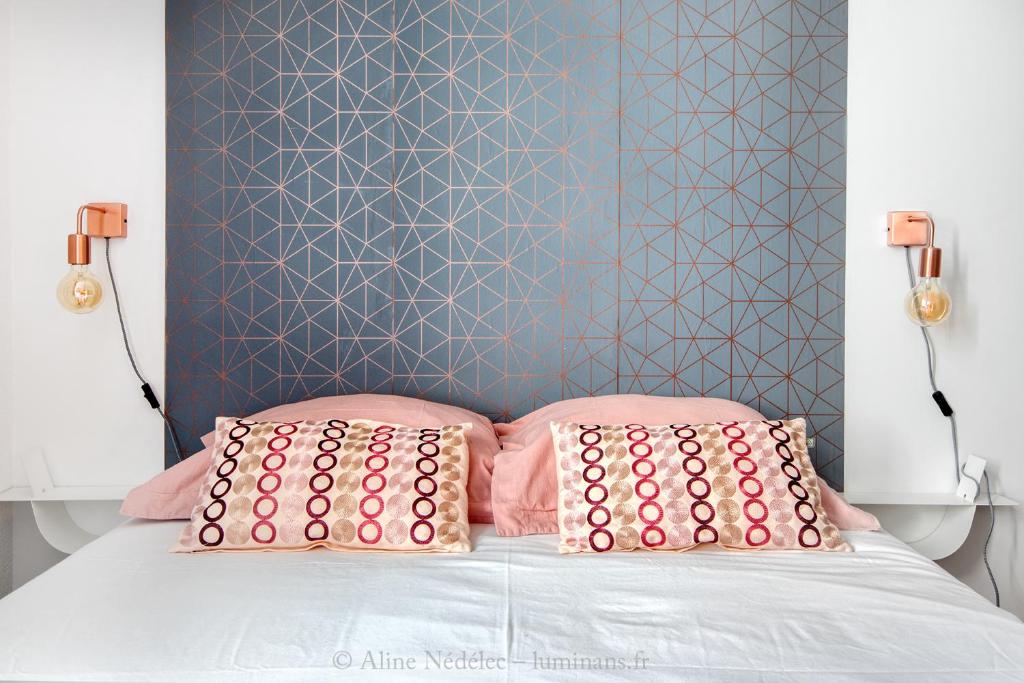 uma cama com almofadas cor-de-rosa e uma parede azul em The Clock House, 3 étoiles em La Rochelle