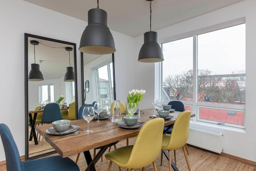 a dining room with a wooden table and yellow chairs at Tyr Apartments by Heimaleiga in Reykjavík