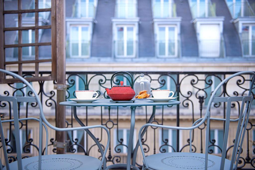 a table with two cups and a tea pot on a balcony at Hôtel Alfred Sommier in Paris