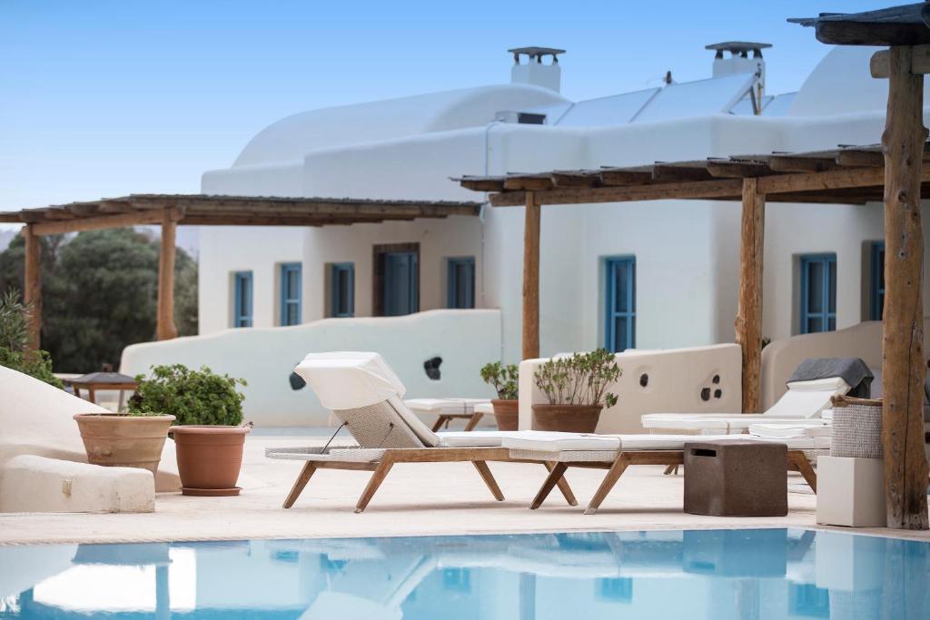 a pool with chairs and a table next to a house at Black Rose Beach Suites in Perivolos