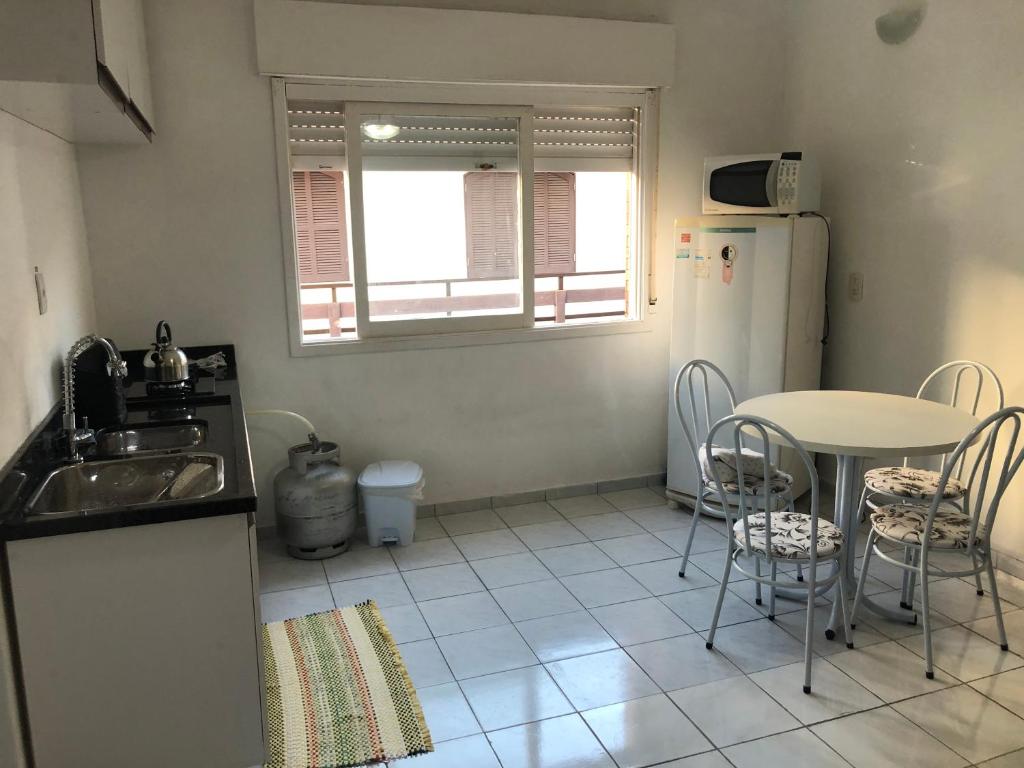a kitchen with a table and a white refrigerator at Ap 408 Beira Mar - Pés na areia in Capão da Canoa