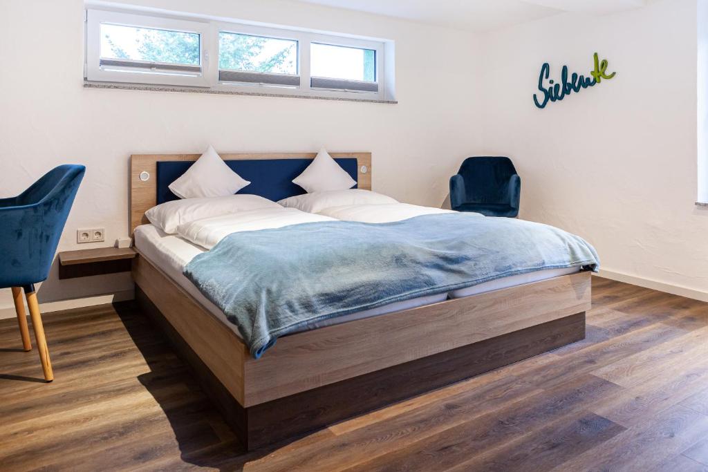 a bedroom with a bed and two blue chairs at Siebente - Gästezimmer Gans im Grünen in Ellscheid