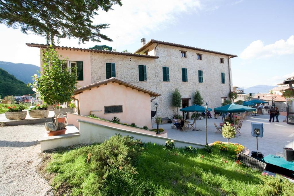 a large white building with a patio in front of it at Dimora della Fonte in Greccio