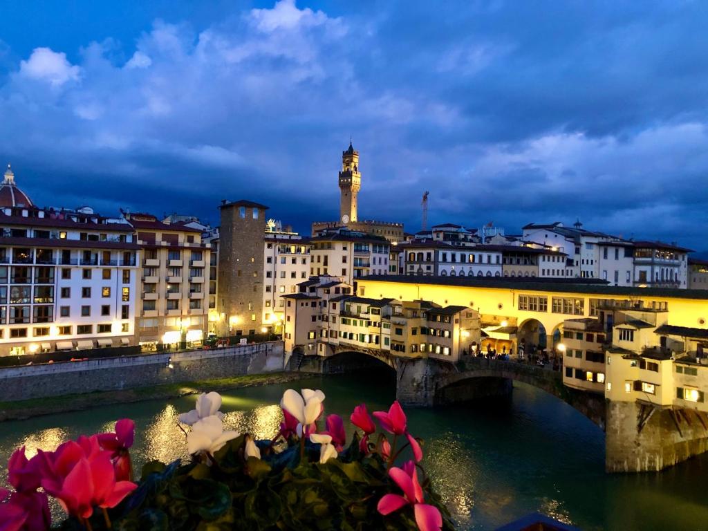 Ponte Vecchio View Luxury Apartment في فلورنسا: جسر فوق نهر في مدينة في الليل