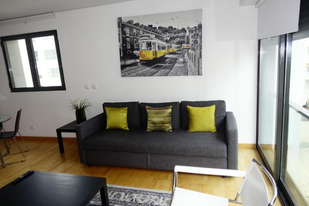 a living room with a gray couch and yellow pillows at Best Apartments Portugal in Lisbon