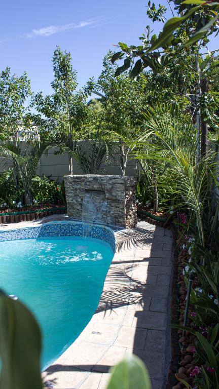 a swimming pool in a garden with a stone wall at Princess Holiday Home in Cape Town