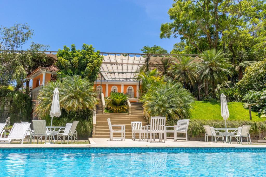 eine Villa mit einem Pool, Stühlen und einem Haus in der Unterkunft Locanda della Mimosa in Petrópolis