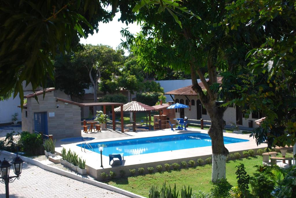 a swimming pool in a yard next to a house at Hotel Rusticos in Conceição da Barra