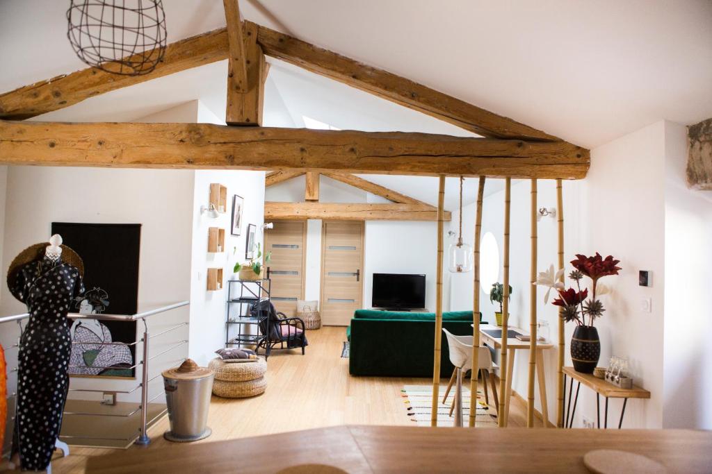 ein Wohnzimmer mit einem grünen Sofa und Holzbalken in der Unterkunft Gîte de l'Autre Jardin in Mirepoix