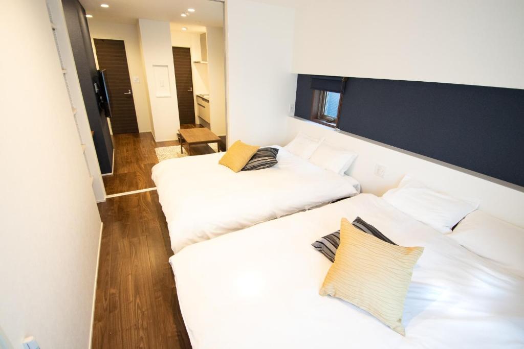 two beds in a room with white sheets and pillows at Apartment Hotel Tenjin TUMUGU / Vacation STAY 62172 in Susakiuramachi