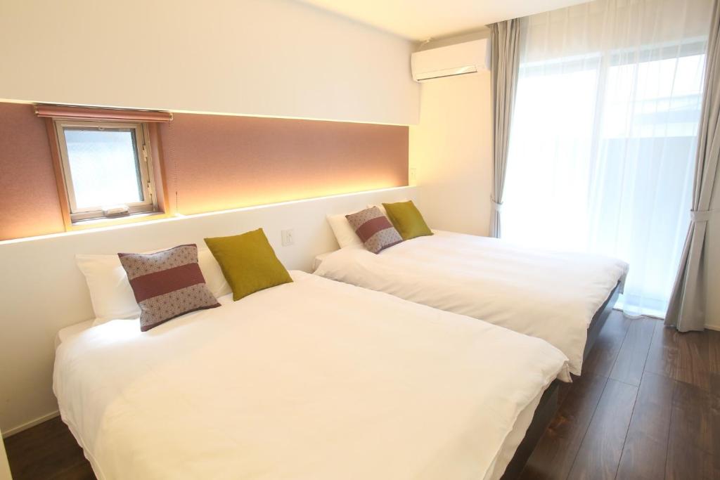 two beds in a hotel room with a window at Apartment Hotel Tenjin TUMUGU / Vacation STAY 62166 in Susakiuramachi