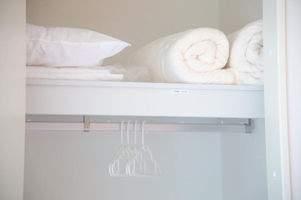 a white shelf with towels and pillows on it at Apartment Hotel Tenjin TUMUGU / Vacation STAY 62181 in Susakiuramachi