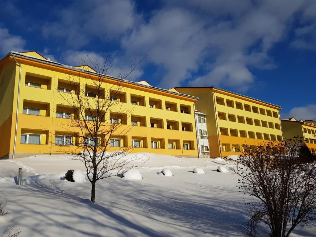 a yellow building with snow in front of it at Lipno-Frymburk Wellnes APT D 103 in Frymburk