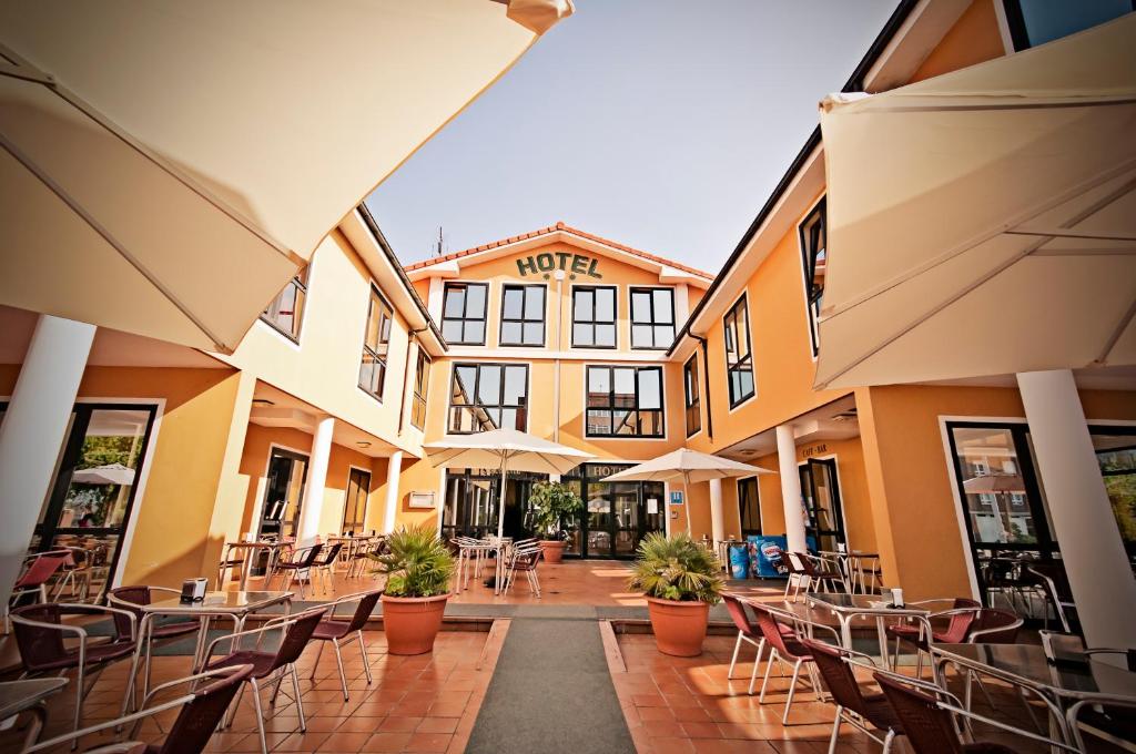 un cortile vuoto con sedie, tavoli e ombrelloni di Hotel Piedras a Piedras Blancas