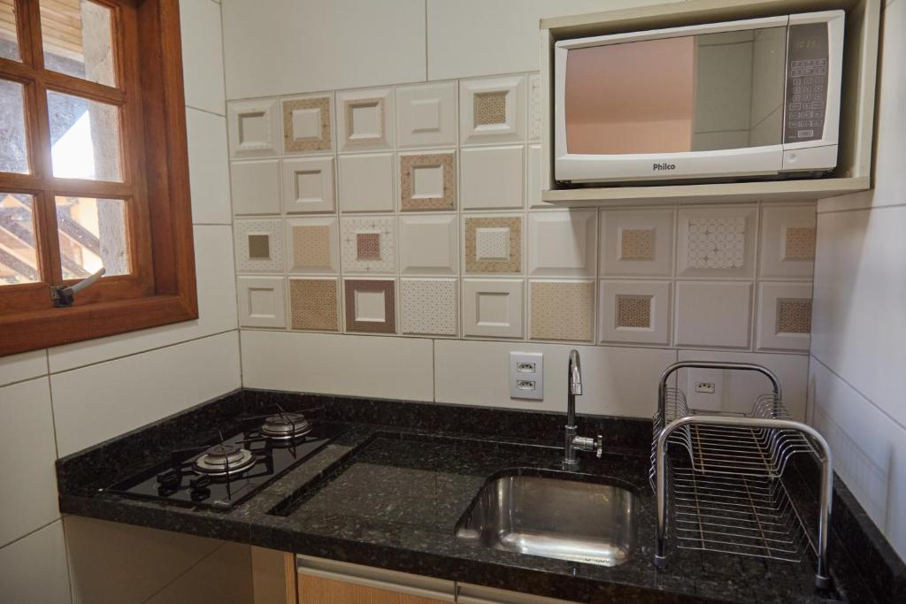 a kitchen with a sink and a microwave at Pousada Lagoa do Rosa in Praia do Rosa