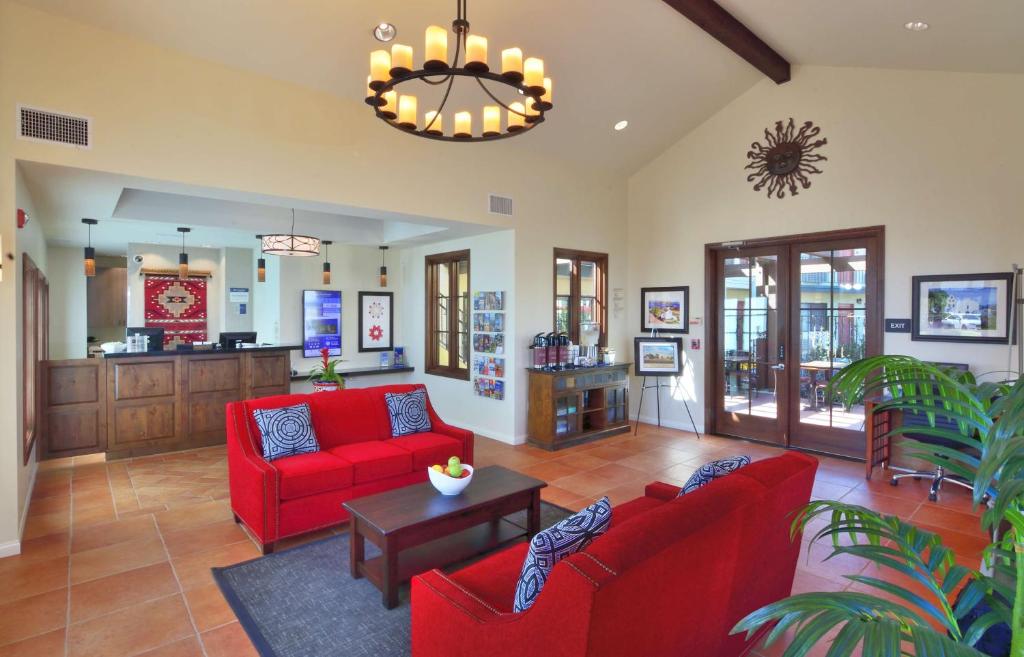 a living room with red couches and a table at Lamplighter Inn & Suites at SDSU in San Diego