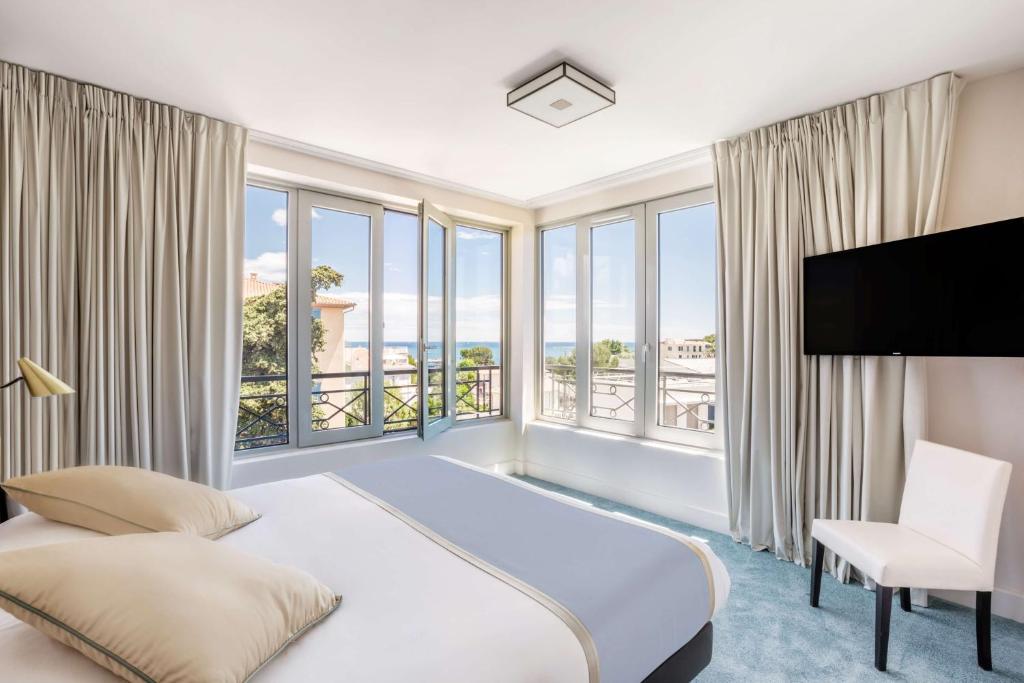 een slaapkamer met een bed en een groot raam bij Best Western Hôtel Journel Antibes Juan-les-Pins in Antibes