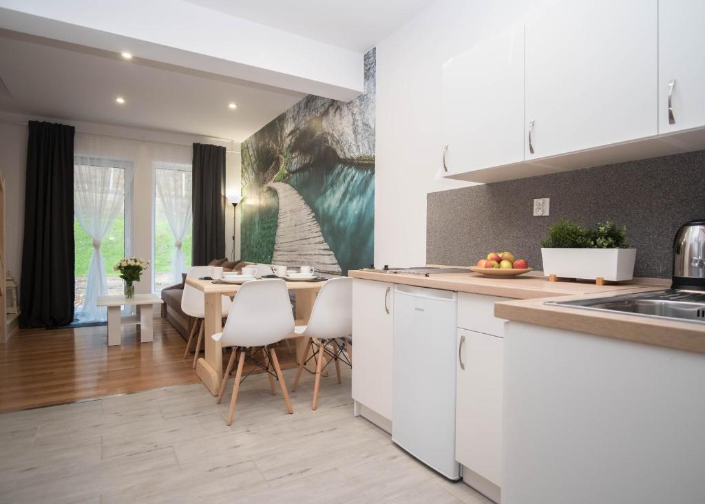 a kitchen and dining room with white cabinets and a table at Apartamenty GoszoWita in Stronie Śląskie