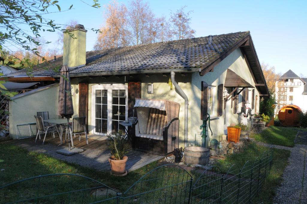 ein kleines weißes Haus mit einer Holzterrasse in der Unterkunft Haus Vis a Vis 1 in Stromberg