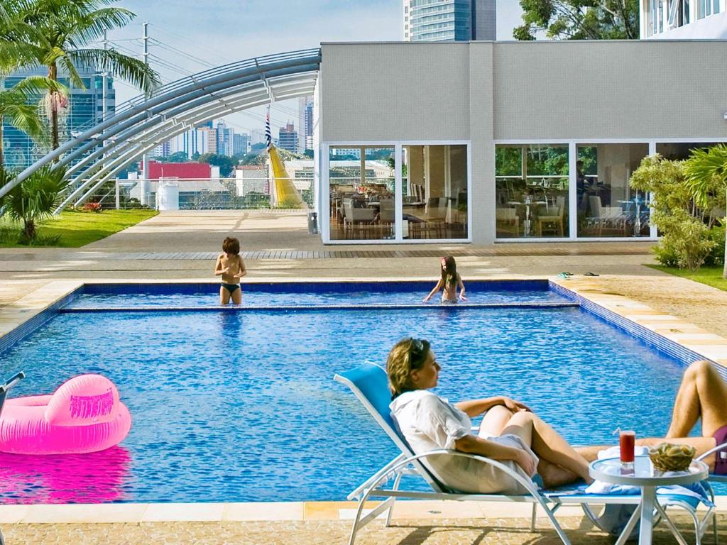 a group of people sitting in chairs in a swimming pool at Novotel Sao Paulo Morumbi in São Paulo