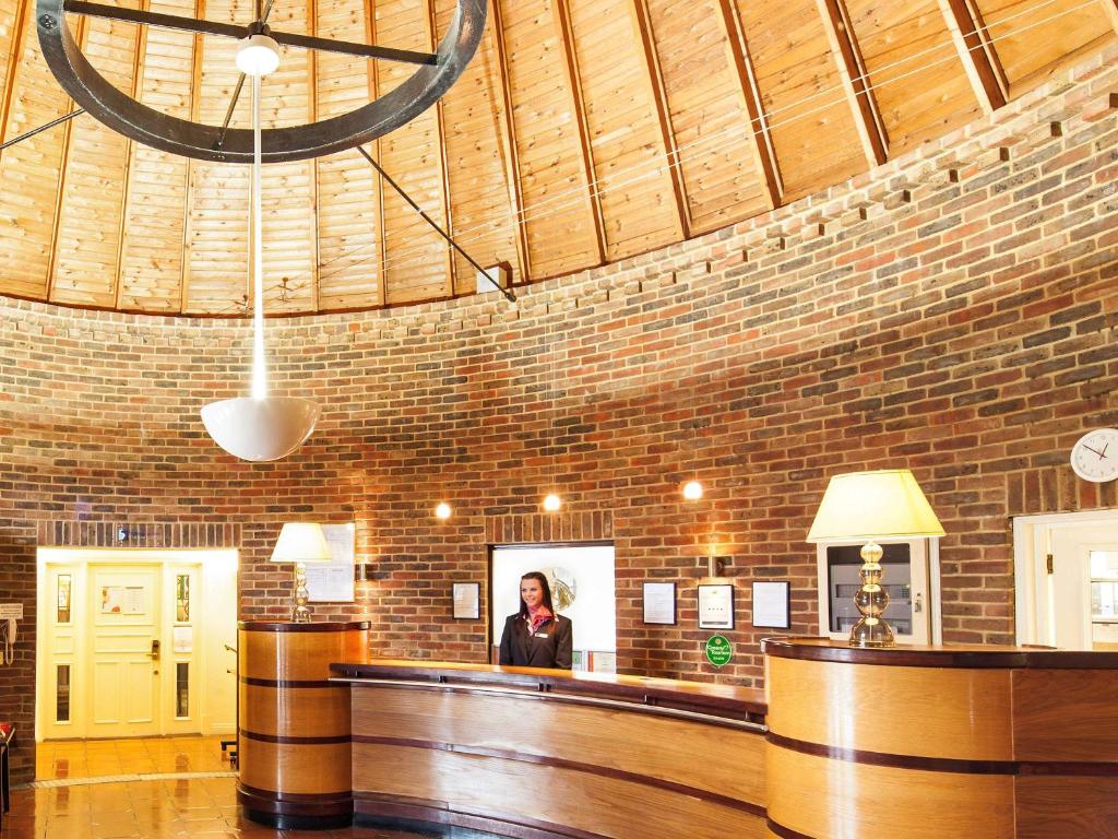 a woman standing at a bar in a brick room at Mercure Tunbridge Wells Hotel in Royal Tunbridge Wells