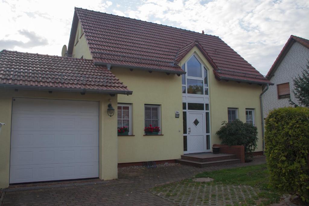 een geel huis met een witte garagedeur bij Ferienhaus Bogsi in Müllrose