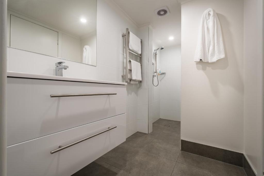 a white bathroom with a shower and a sink at Argosy Motor Inn in Devonport