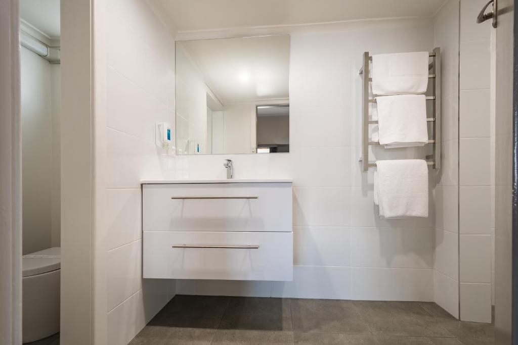a white bathroom with a sink and a mirror at Argosy Motor Inn in Devonport