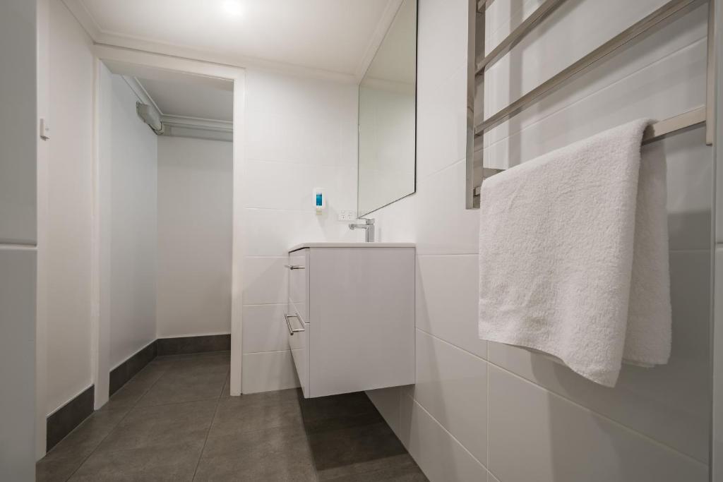 a white bathroom with a sink and a towel at Argosy Motor Inn in Devonport