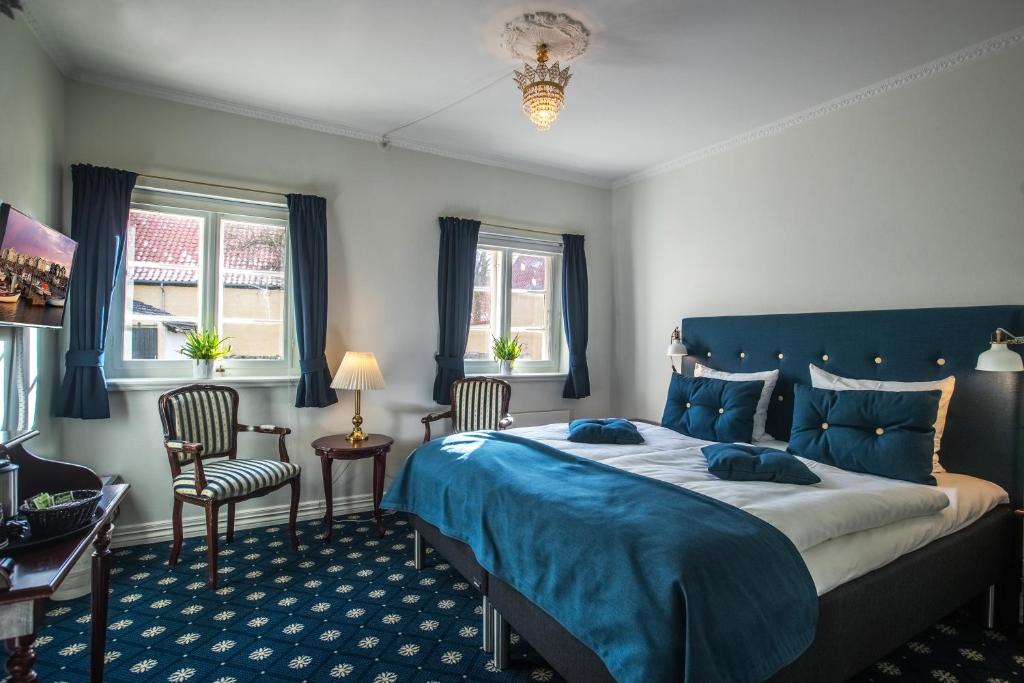 Hotel Postgaarden i Mariager في Mariager: غرفة نوم بسرير كبير وكرسيين
