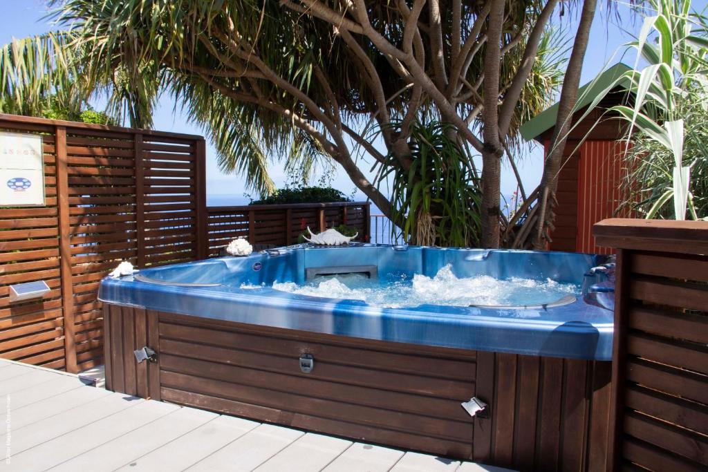 a jacuzzi tub in a backyard with a fence at Residence Les Lataniers in Saint-Leu